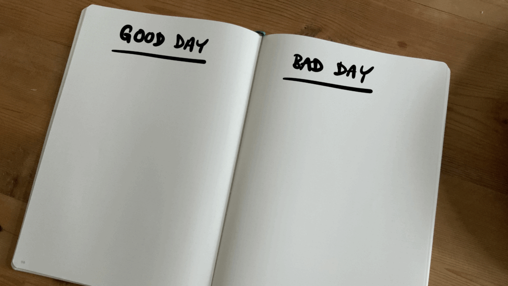 An open notebook with the heading 'good day' written on the left hand page and 'bad day' written on the right hand page