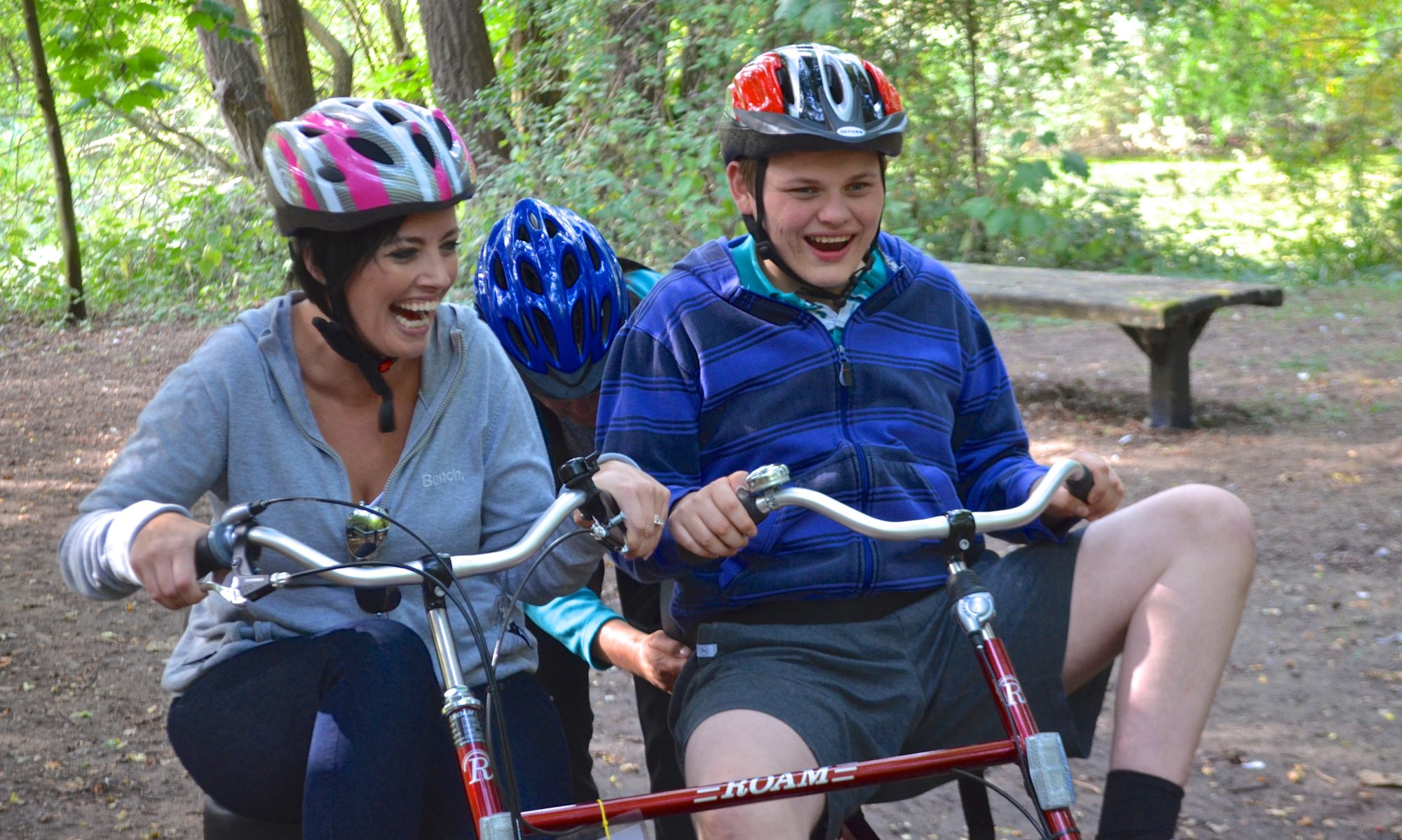 Carer and young adult on bike in country park